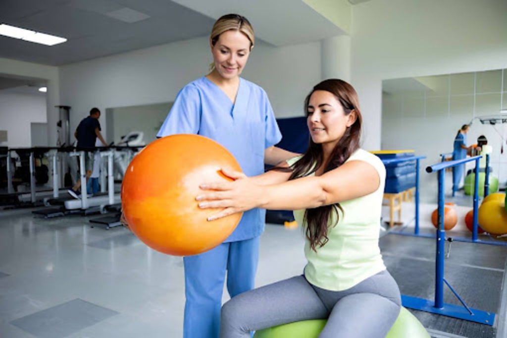 Physical therapist guiding a woman through an exercise ball stretch during a recovery and wellness session.