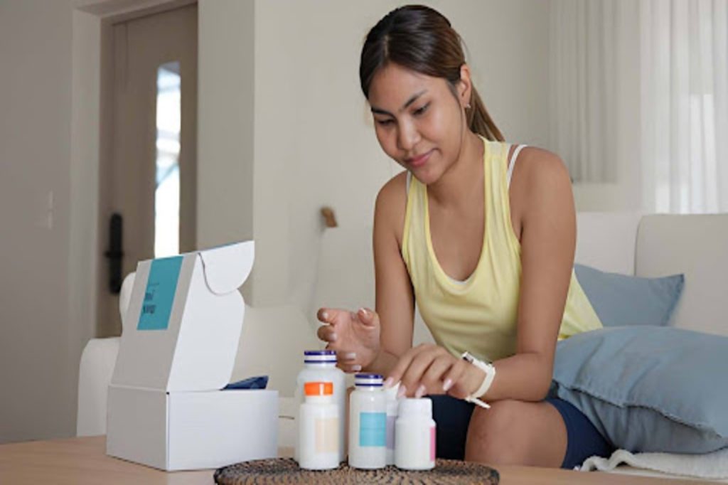 Woman preparing wellness supplements at home with vitamin bottles, a syringe, and a treatment kit on the table.